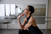 Ballerina in graceful pose looking up and touching chin \n