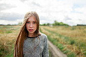 Portrait of young blond woman looking at camera in field \n