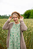 Portrait einer jungen Frau mit Baskenmütze in einem Weizenfeld stehend