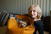 Portrait einer Frau mit Yorkshire-Terrier, der in einer Tasche sitzt