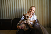Portrait of woman holding Yorkshire terrier in living room \n