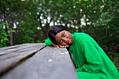 Woman leaning on picnic table and looking at camera \n