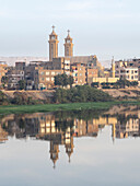 A view of the shoreline along the upper Nile River, with town and church reflection, Dendera, Egypt, North Africa, Africa\n