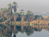 Fishermen in a small boat on the upper Nile River, amongst some of the most verdant land along the river, Egypt, North Africa, Africa\n