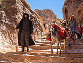 Donkeys, guide and tourists on the path to The Petra Monastery (Al Dayr), Petra Archaeological Park, UNESCO World Heritage Site, one of the New Seven Wonders of the World, Petra, Jordan, Middle East\n
