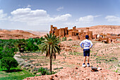 Rear view of boy admiring an old kasbah, Ounila Valley, Atlas mountains, Ouarzazate province, Morocco, North Africa, Africa\n