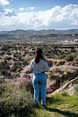 Junge Frau mit Blick auf die Wüste von Tabernas an einem sonnigen Tag, Almeria, Andalusien, Spanien, Europa