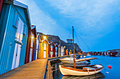 Bunte Fischerhütten mit Holzboot am Steg in der Abenddämmerung,Smogen,Bohuslan,Vastra Gotaland,Westschweden,Schweden,Skandinavien,Europa