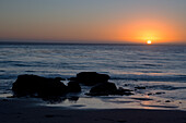Sonnenuntergang über dem Meer, mit Felsen im Vordergrund, San Simeon, Kalifornien, Vereinigte Staaten von Amerika, Nordamerika