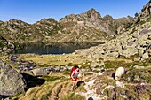 France, Hautes Pyrenees, start of the ascent of the Pic du Turon de Neouvielle (3035m), the Glère lake (2103m) and refuge of the glère in the background\n