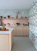 Light-colored kitchen with pastel green floral wallpaper and pink tiled backsplash