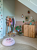 Children's room with wooden wardrobe, clothes rack and seat cushion