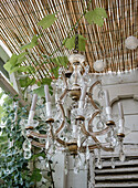 Crystal chandelier under a bamboo roof with ivy and fairy lights