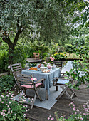 Wooden table set with flowers and pasties by the pond