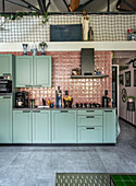 Kitchen with mint green cupboards and pink retro-style tiles