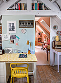 Desk corner with yellow chair and view of another room in the attic