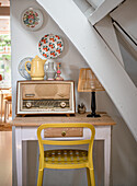 Vintage radio on a small table with yellow chair under the stairs