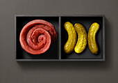 Tray with raw meat rolls and gherkins