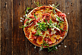 Wholemeal pizza with four types of cheese, sun-dried tomatoes, bresaola and rocket salad