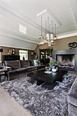 Living room with brown sofas, fireplace and modern pendant lights