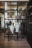 Modern side tables with white porcelain vases in front of a glass door