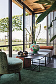 Living area with floor-to-ceiling windows, green carpet and vintage furniture