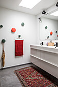 Modern bathroom with colourful wall hooks and oriental rug