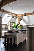 Kitchen island with modern pendant light, wooden beams and skylight