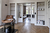 Living room with herringbone parquet flooring, beige leather armchair and sliding doors