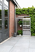 Small greenhouse on red brick wall next to modern patio door