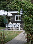 Garden dining area with table and chairs in front of wooden shed