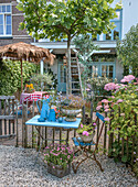 Inviting seating area in the garden with blue table, chair and flower arrangement