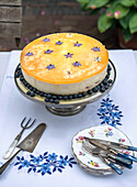 Käsekuchen mit Blaubeeren und essbaren Blüten auf gestickter Tischdecke