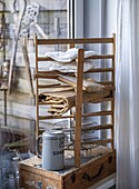 Wooden shelf with folded linen cloths and metal jug