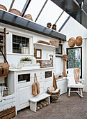 Country-style conservatory with white furniture, baskets and wooden decor