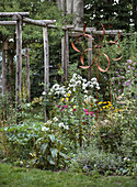 Flowerbed with metal windmill and wooden trellis in the garden