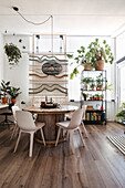 Dining area with macramé wall hanging and plants on a metal shelf