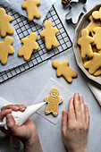 Female hands decorating gingerbread men with icing