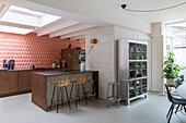 Modern, open-plan kitchen with skylight, kitchen island and bar stools