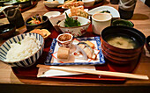 Japanese food on a tray with rice, fish and lotus pickles