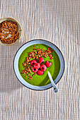 Green smoothie bowl with granola and raspberries