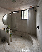Round shower in minimalist bathroom with concrete walls