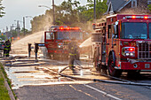 Firefighters spraying water on fire trucks