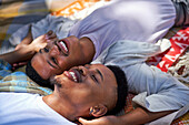 Happy young gay male couple on picnic blanket