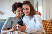 Happy lesbian couple using smart phone