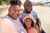 Happy gay male couple with daughter on beach