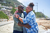 Gay male couple hugging on beach