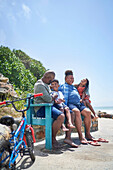 Family sitting on bench on beach