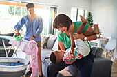 Happy lesbian couple playing with son and ironing