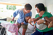 Happy lesbian couple playing with son and ironing